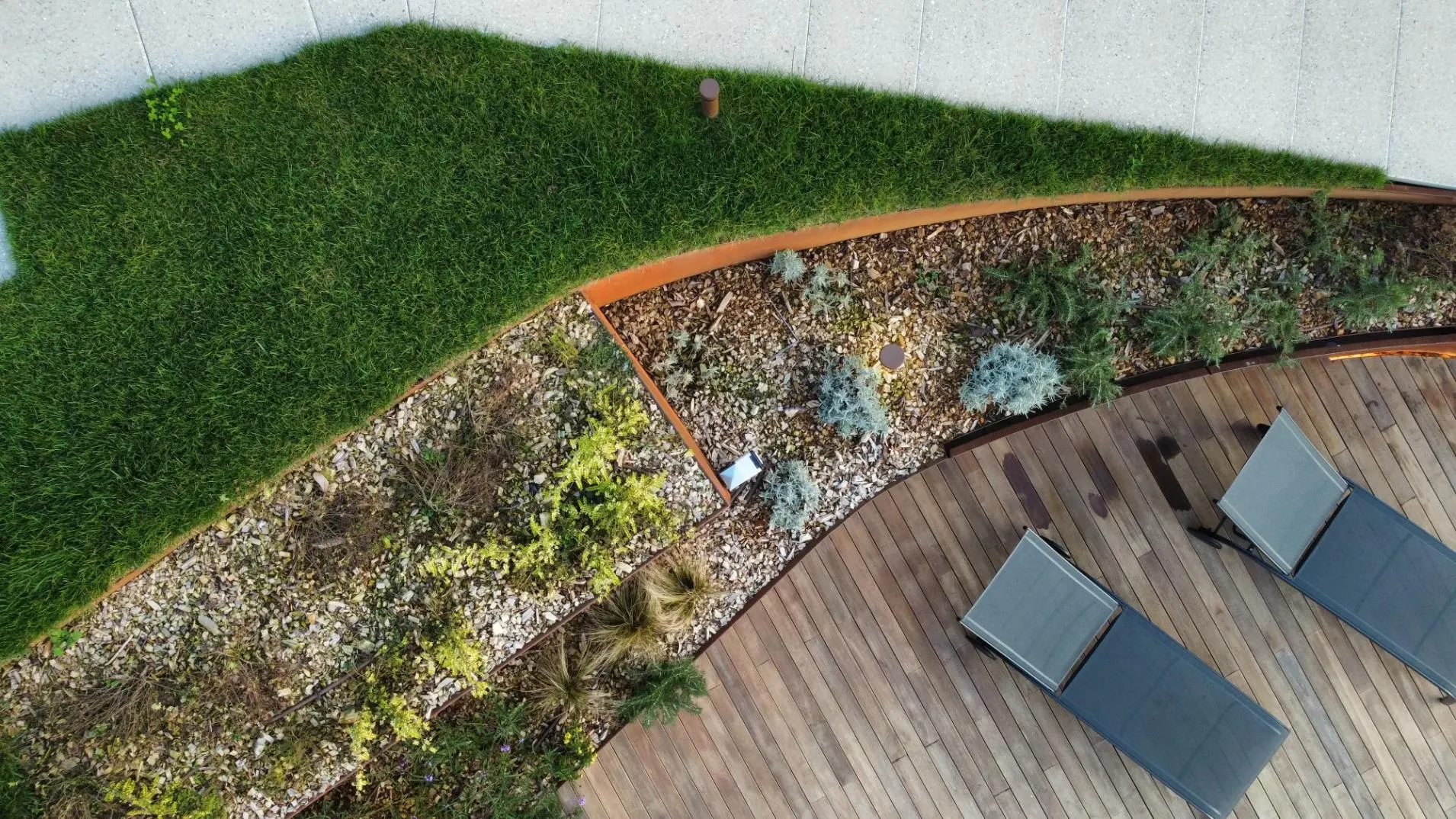 Giardino con piante, ghiaia e deck in legno visto dall'alto