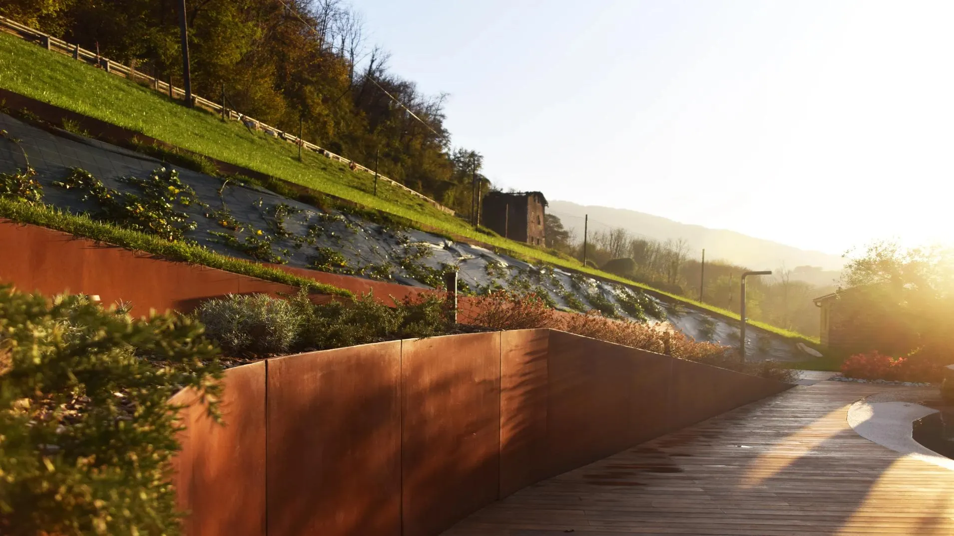 Muro in acciaio corten e giardino in pendenza al tramonto